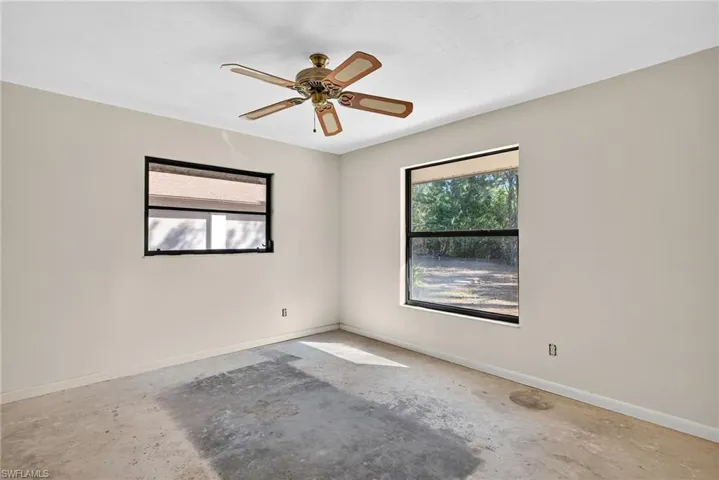 Unfurnished room with unfinished concrete floors, plenty of natural light, and a ceiling fan