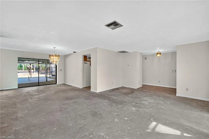 Spare room featuring a chandelier and unfinished concrete floors