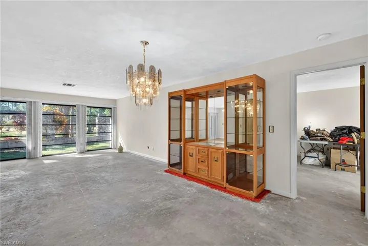 Dining space with unfinished concrete flooring and a chandelier
