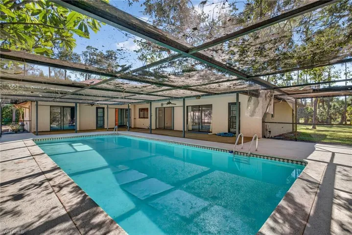 Rear view of house with a lanai, an outdoor pool, a patio, and stucco siding