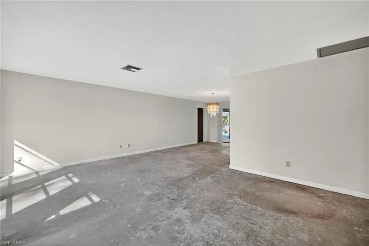 Unfurnished room with a chandelier and unfinished concrete floors