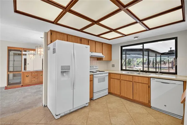 Kitchen with white appliances, light countertops, a chandelier, tasteful backsplash, and brown cabinets