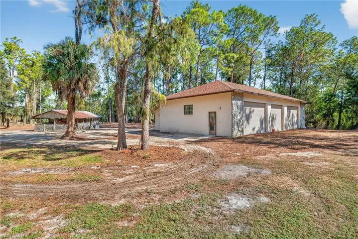 View of side of property with stucco siding, an outbuilding, and view of wooded area