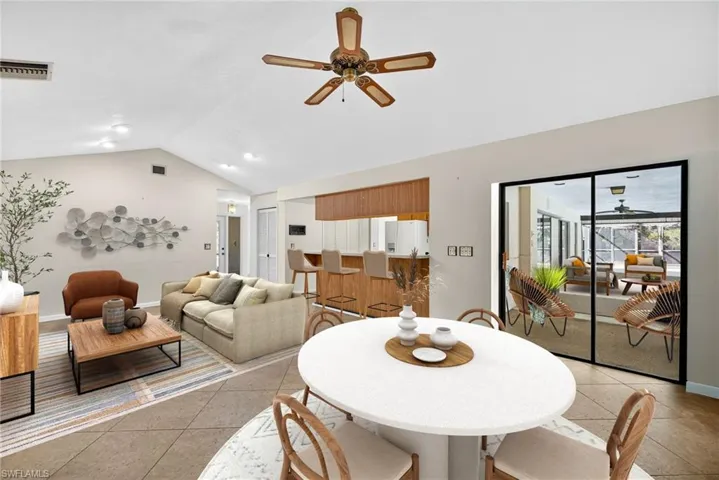Virtually Staged Dining area featuring a ceiling fan, vaulted ceiling, light tile patterned floors, and a sunroom