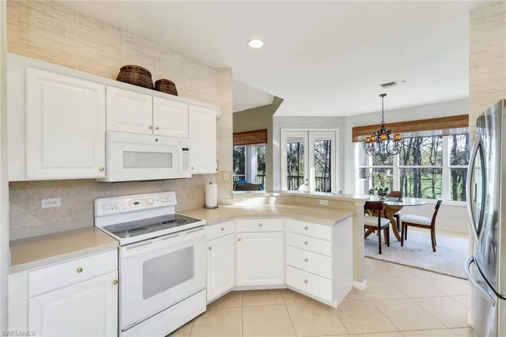 Kitchen with white appliances, light countertops, and a peninsula