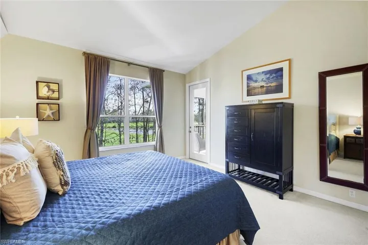 Carpeted bedroom featuring lofted ceiling and access to exterior