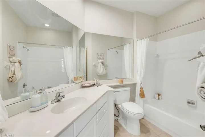 Bathroom featuring vanity, shower / bath combination with curtain, and light tile patterned flooring
