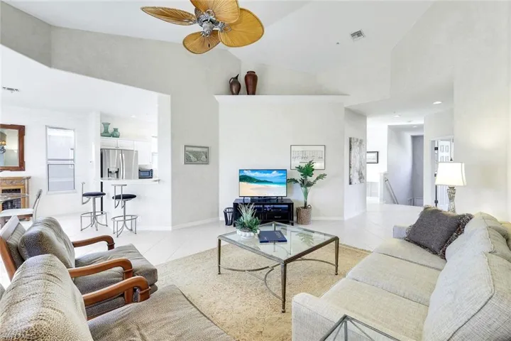 Living room with ceiling fan, a high ceiling, light tile patterned floors, and recessed lighting