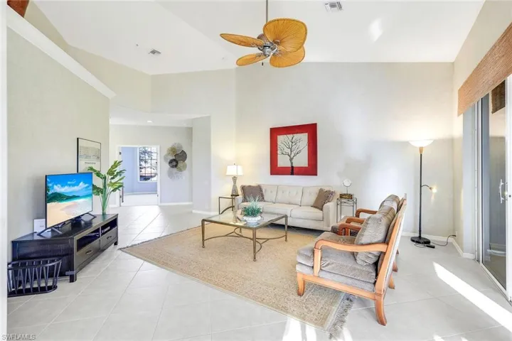 Living area with a ceiling fan, light tile patterned floors, and a high ceiling