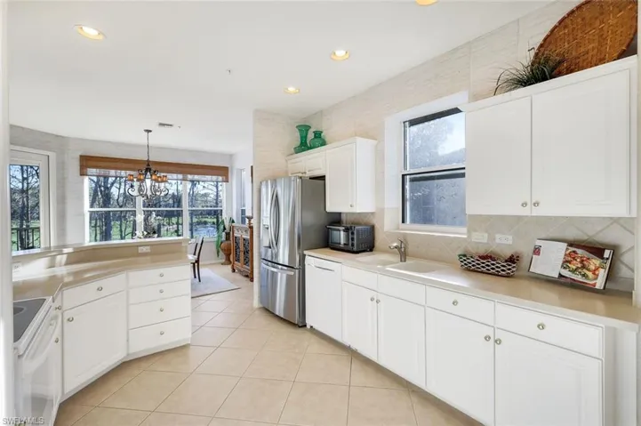 Kitchen featuring white cabinets, healthy amount of natural light, white appliances, and light countertops
