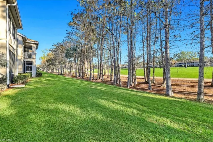 View of grassy yard featuring a balcony