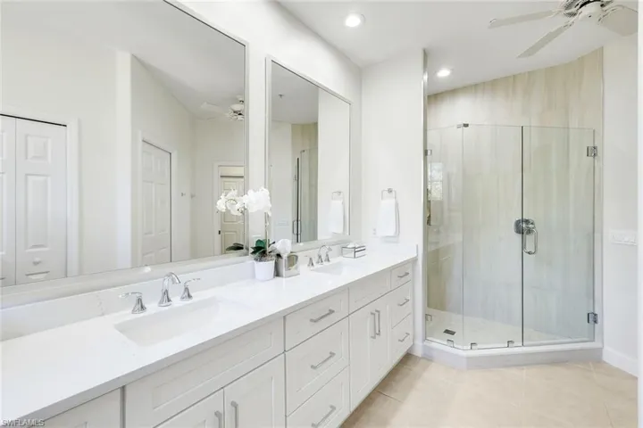 Bathroom featuring a ceiling fan, double vanity, a stall shower, light tile patterned floors, and recessed lighting