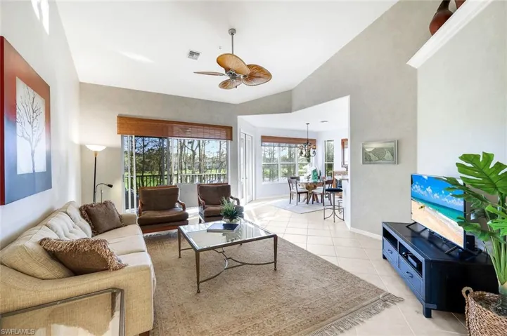 Living room with ceiling fan, vaulted ceiling, and light tile patterned floors