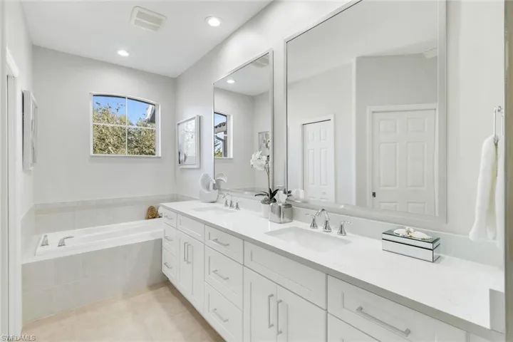 Bathroom with double vanity, a garden tub, light tile patterned flooring, and recessed lighting