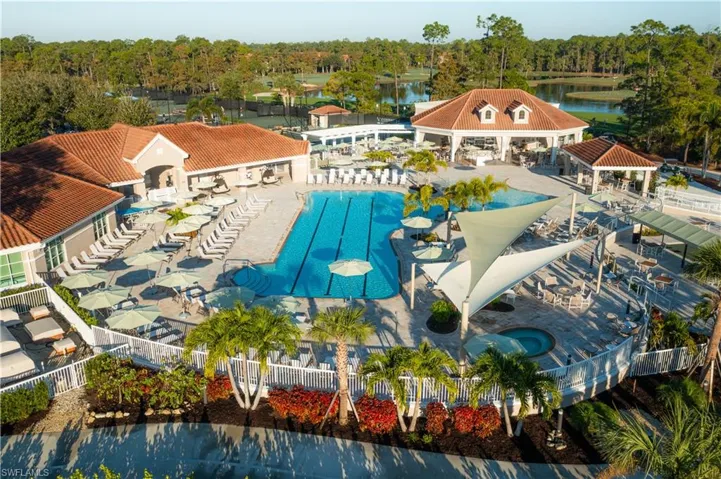 Community pool with a patio and view of wooded area
