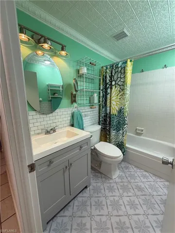 Bathroom featuring a patterned tile floor, white subway tile accent wall, and a full-size bathtub with white tile surround