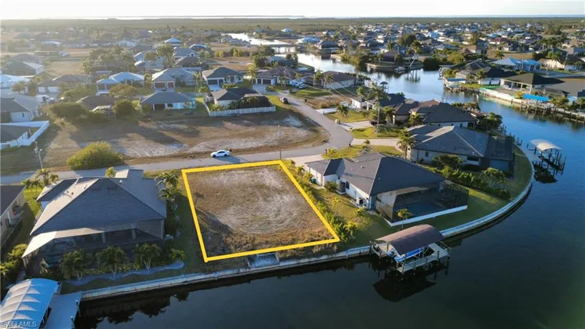 Aerial perspective of suburban area featuring property boundaries highlighted and a large body of water