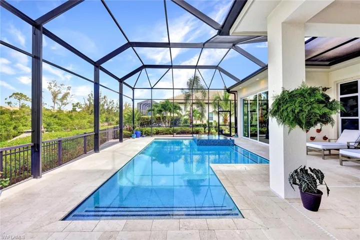 View of pool with a patio area and large screen enclosure