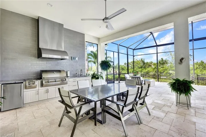 View of patio featuring glass enclosure, ceiling fan, grilling area, area for grilling, and sink