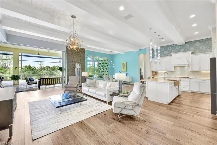 Living room featuring beam ceiling, light wood-flooring, crown molding