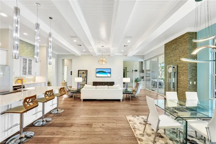 Dining room featuring light hardwood / wood-style floors, crown molding, beamed ceiling, and a chandelier