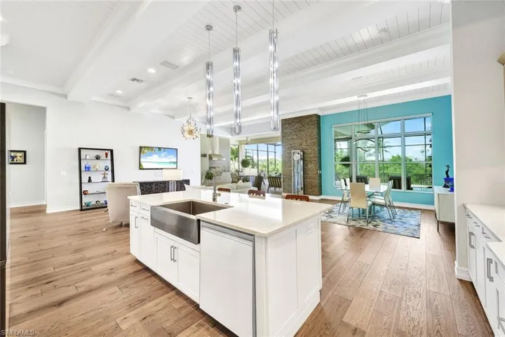 Kitchen with an island with sink, white dishwasher, sink, pendant lighting, and wood cabinets