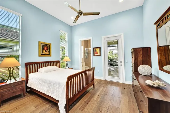 Bedroom featuring ensuite bath, access to outside, light wood-type flooring, and ceiling fan