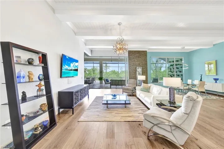Living room with light hardwood / wood-style flooring, a chandelier, and beamed ceiling