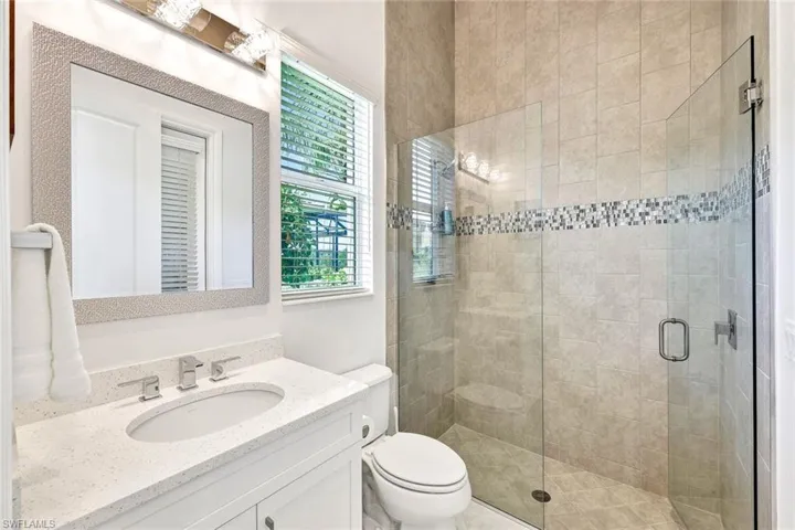Bathroom/ pool bath featuring vanity, toilet, and a glass shower door