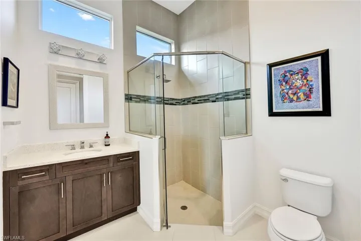 Bathroom featuring toilet, vanity, tile patterned floors, and a shower with door