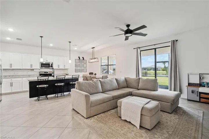 Living room featuring a ceiling fan, light tile patterned flooring, and recessed lighting