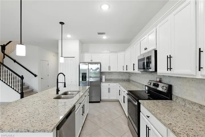 Kitchen featuring stainless steel appliances, white cabinetry, decorative backsplash, and recessed lighting