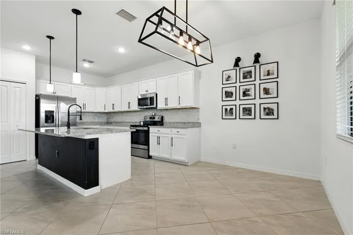 Kitchen featuring stainless steel appliances, backsplash, white cabinets, light stone counters, and recessed lighting