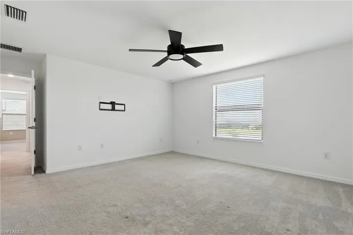 Carpeted empty room featuring healthy amount of natural light and ceiling fan
