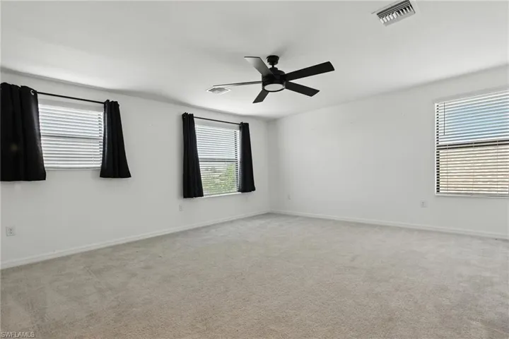 Carpeted empty room with ceiling fan and baseboards
