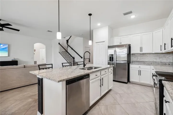 Kitchen with stainless steel appliances, light stone counters, white cabinets, and recessed lighting