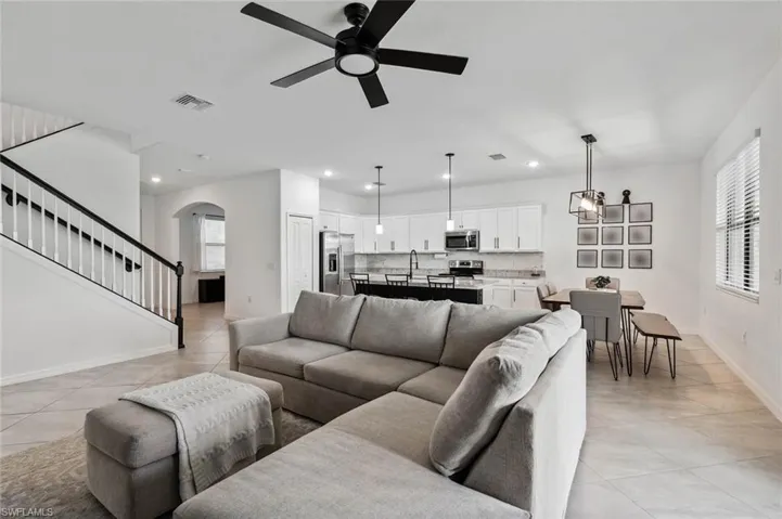 Living area featuring arched walkways, stairway, light tile patterned flooring, ceiling fan, and recessed lighting