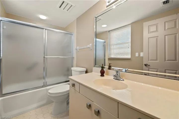 Full bath with vanity, enclosed tub / shower combo, light tile patterned floors, and recessed lighting