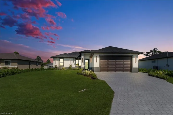 Prairie-style home with a front lawn, decorative driveway, stucco siding, a garage, and roof with shingles