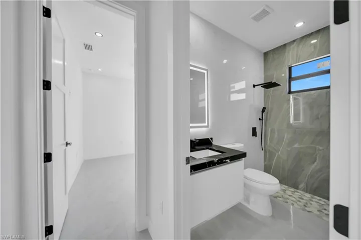 Full bath featuring a marble finish shower, vanity, and recessed lighting