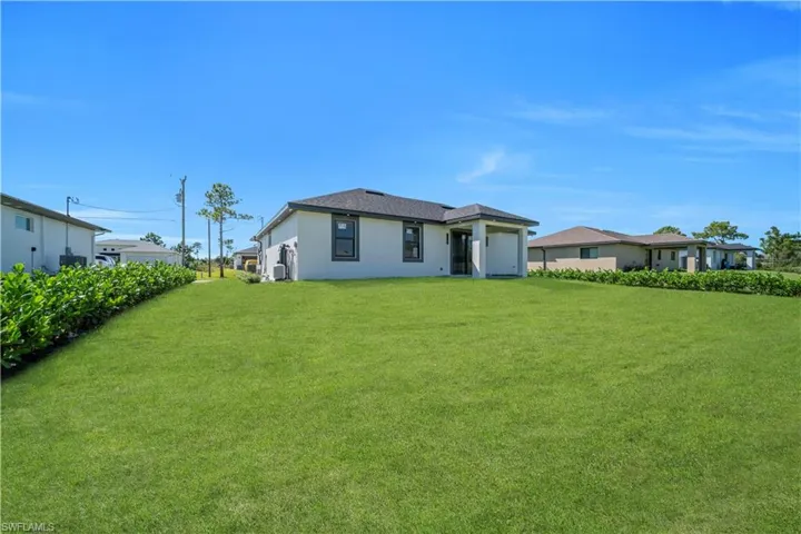 Back of property featuring a yard and stucco siding