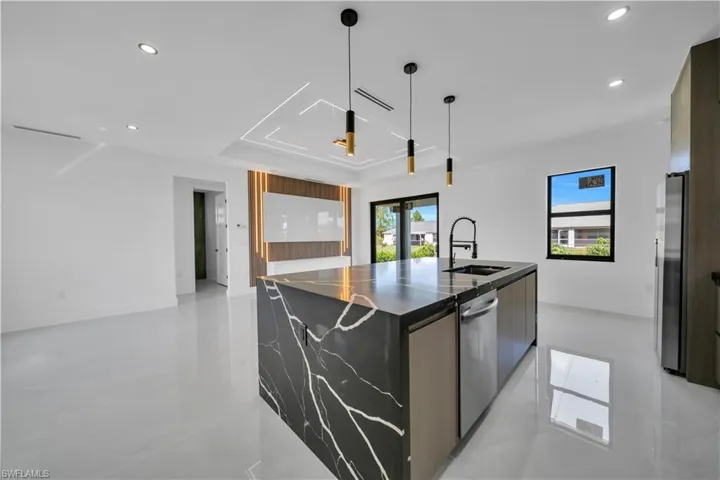 Kitchen featuring modern cabinets, a large island with sink, decorative light fixtures, and stainless steel appliances