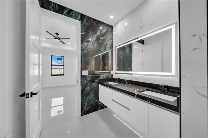 Full bath with double vanity, stone wall, recessed lighting, and tile walls