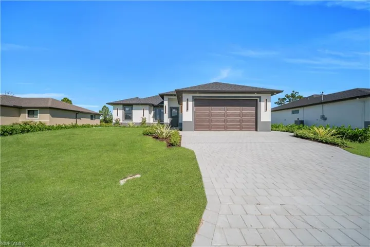 Prairie-style house with a front lawn, driveway, an attached garage, and stucco siding