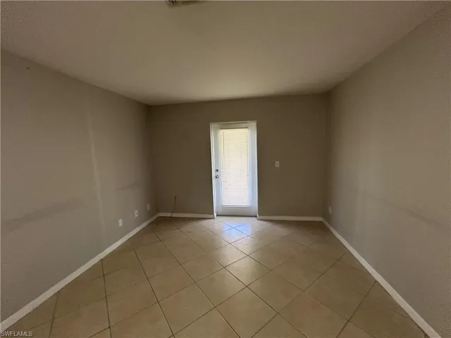 Unfurnished room featuring light tile patterned floors and baseboards