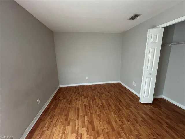 Unfurnished bedroom featuring dark wood finished floors and a closet