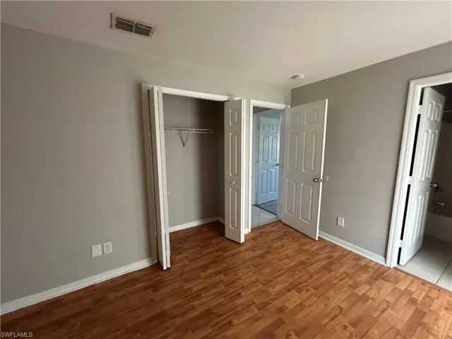 Unfurnished bedroom featuring wood finished floors, ensuite bathroom, and a closet