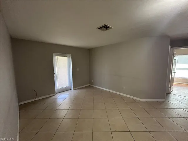 Empty room with light tile patterned floors and baseboards