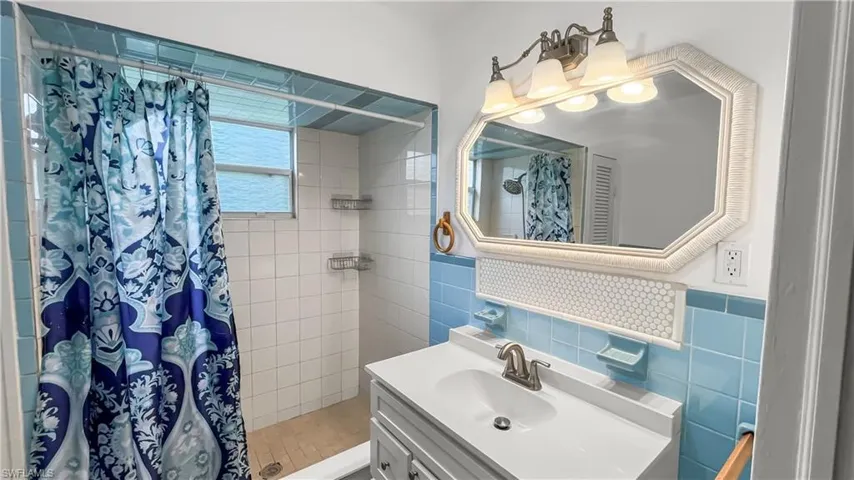 Bathroom featuring tile walls, vanity, and a shower with curtain