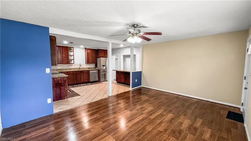 Kitchen with appliances with stainless steel finishes, ceiling fan, a textured ceiling, and light hardwood / wood-style flooring